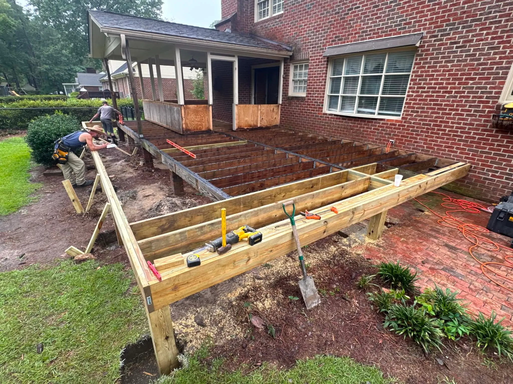Deck frame under construction beside a brick home