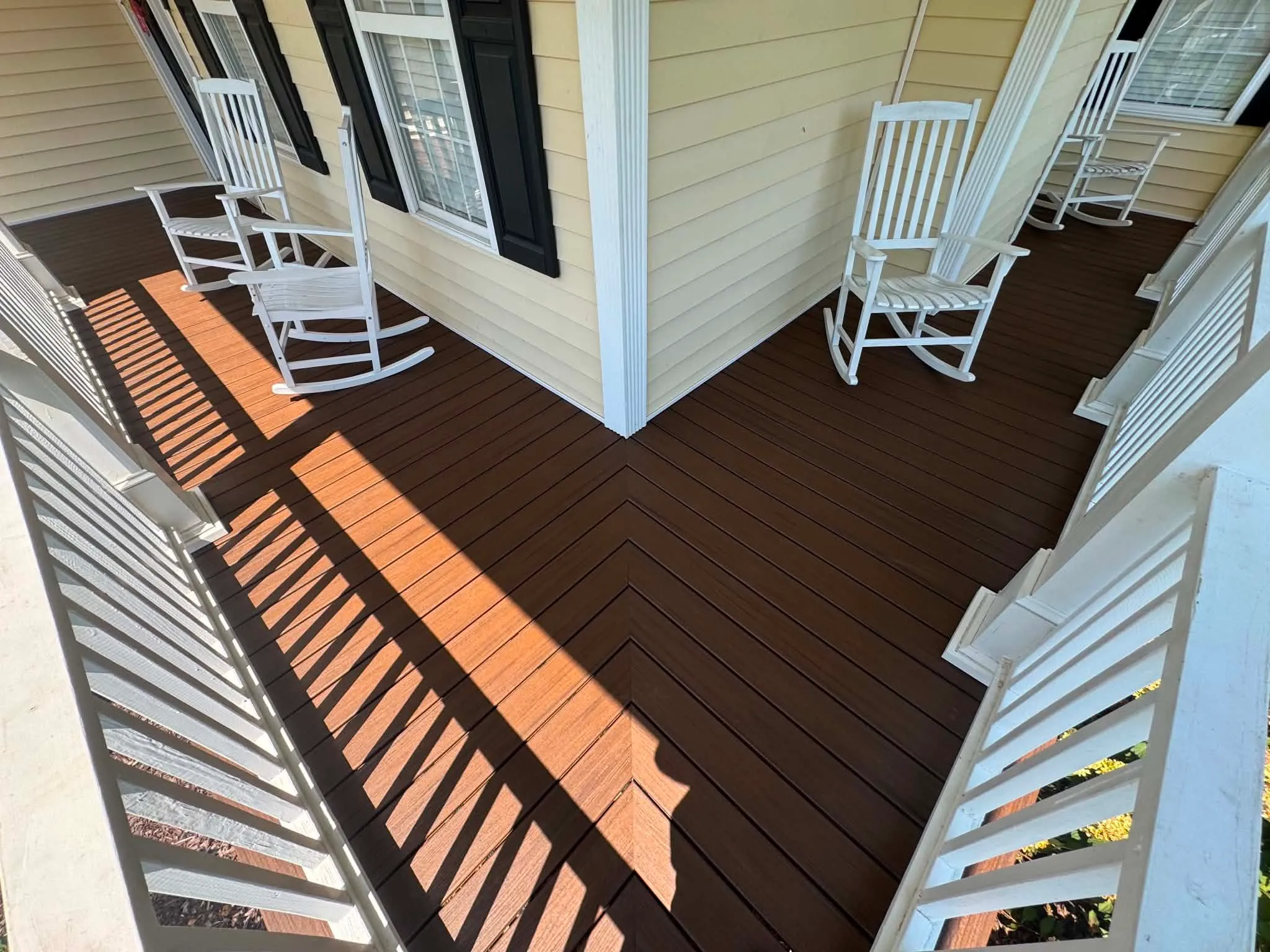 Brown deck surface beside a porch and white railing